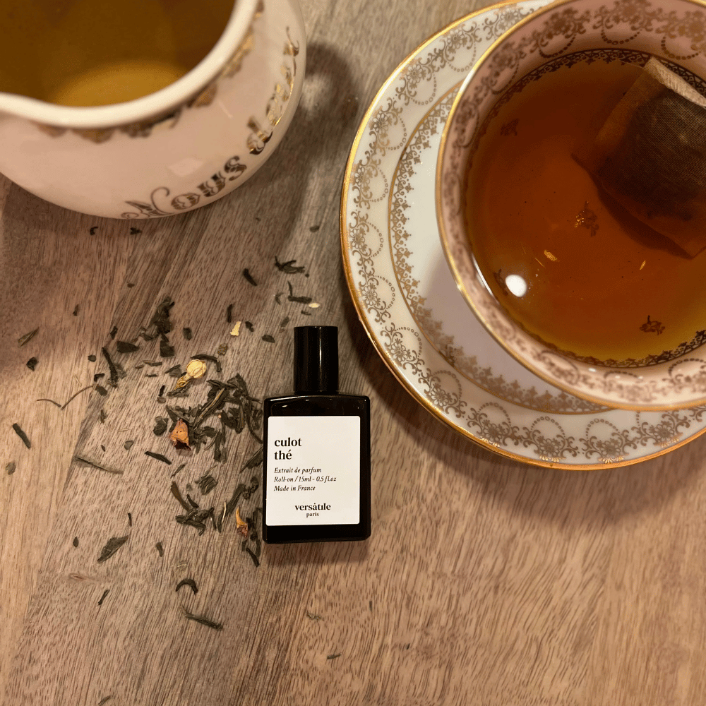 Au centre le flacon de Culot thé de la marque Versatile Paris mis en scène avec une théière et une tasse de thé au jasmin