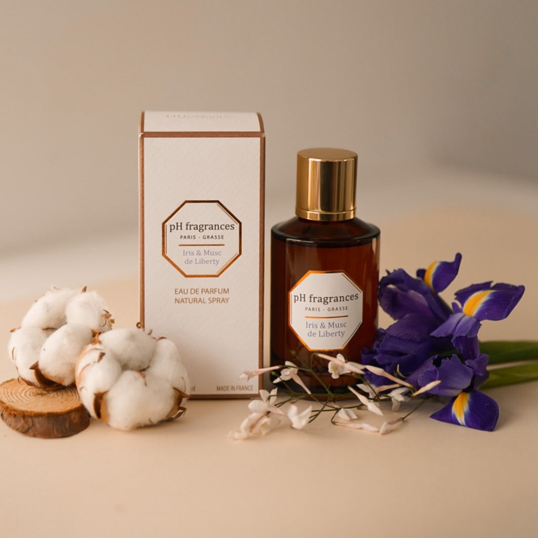 L'eau de parfum Iris & Musc de Liberty de la marque pH Fragrances au centre entouré des éléments qui le composent : musc, iris, fleur de coton...