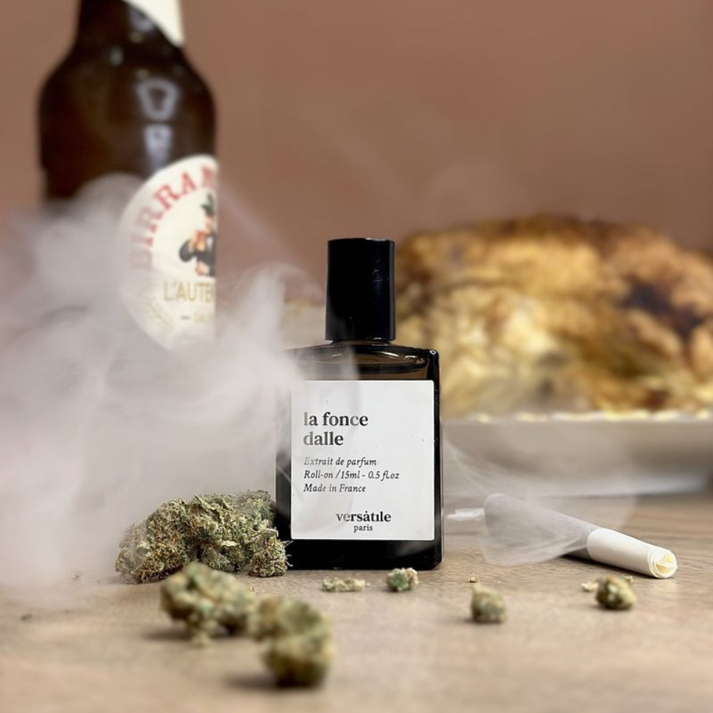 Au centre le flacon de parfum à base d'huile La Fonce Dalle de la marque Versatile Paris mis en scène avec un poulet rôti dans le fond, une bière et du cannabis (CBD)